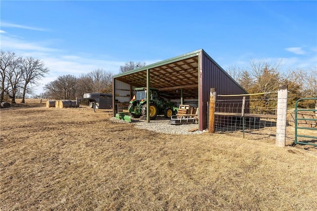 view of outdoor structure with an outbuilding, a carport, a rural view, and an exterior structure