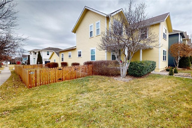 view of front of house featuring a front yard, fence, and a residential view