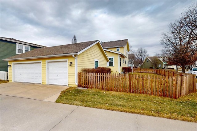 view of home's exterior with a garage, driveway, and a fenced front yard