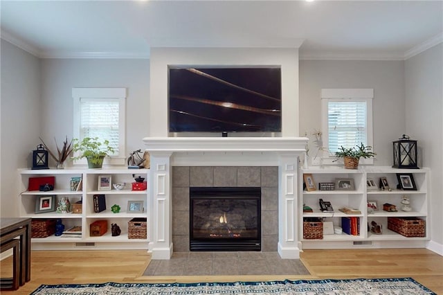 living area with a tile fireplace, a healthy amount of sunlight, and wood finished floors