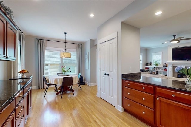 kitchen with light wood finished floors, recessed lighting, dark stone counters, and decorative light fixtures