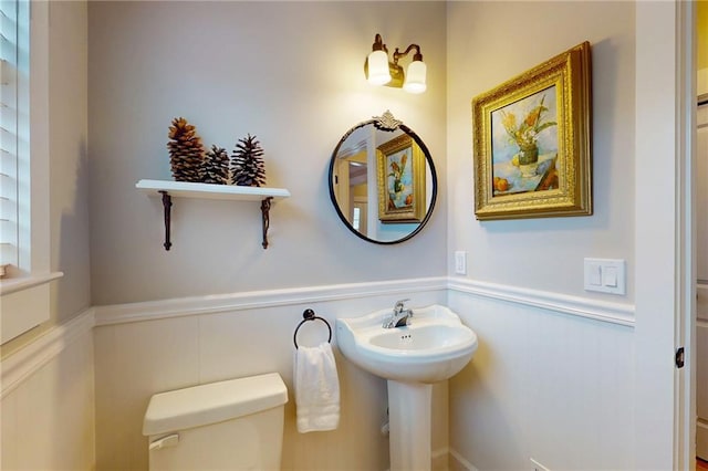 bathroom featuring toilet and a wainscoted wall