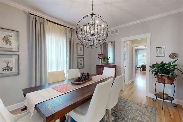 dining space featuring light wood finished floors, baseboards, visible vents, ornamental molding, and an inviting chandelier