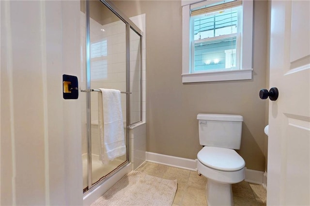 bathroom with a stall shower, tile patterned floors, toilet, and baseboards