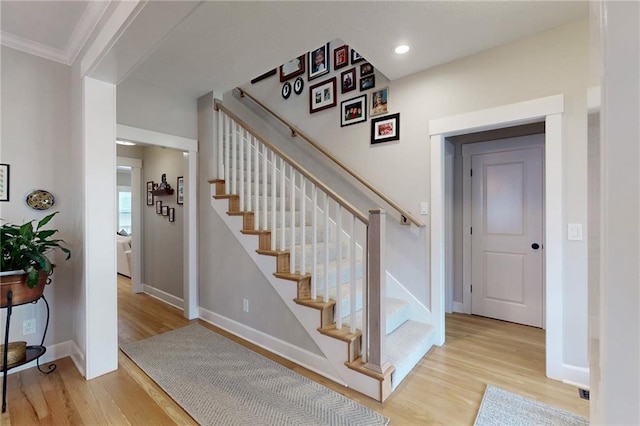 staircase with ornamental molding, recessed lighting, wood finished floors, and baseboards