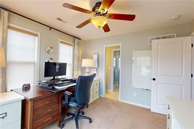 office space with baseboards, a ceiling fan, visible vents, and light colored carpet