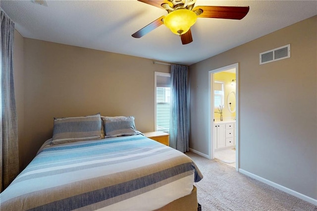 bedroom featuring visible vents, ensuite bathroom, a ceiling fan, light carpet, and baseboards