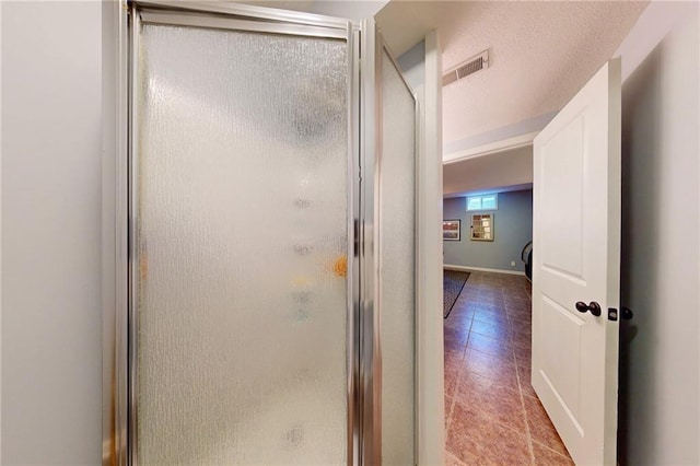 full bathroom featuring a textured ceiling, tile patterned flooring, a shower stall, and visible vents