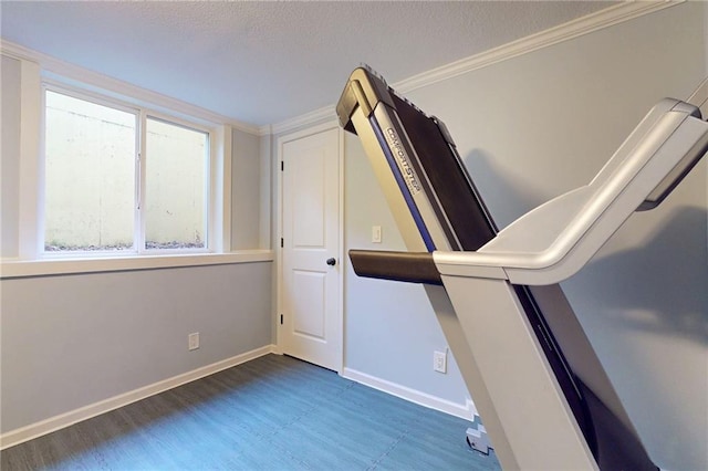 unfurnished bedroom with crown molding, a textured ceiling, wood finished floors, and baseboards