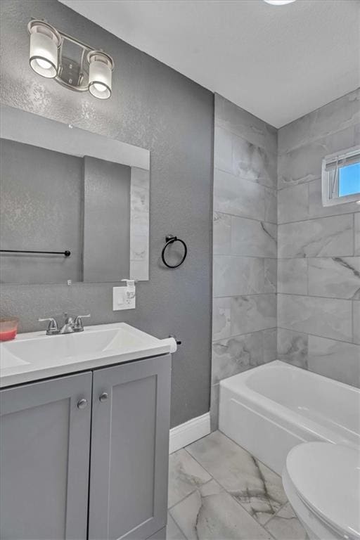 full bathroom featuring vanity, tiled shower / bath, and toilet