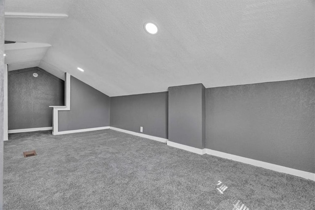 bonus room featuring lofted ceiling, carpet flooring, and a textured ceiling