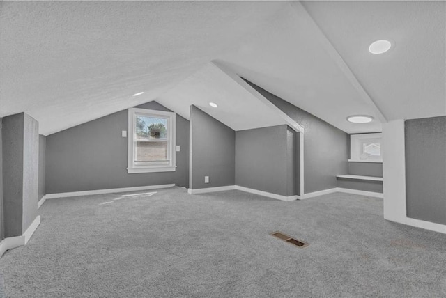 bonus room featuring vaulted ceiling, carpet floors, and a textured ceiling