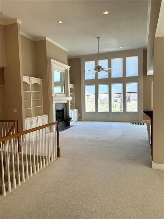 carpeted living area with recessed lighting, a fireplace with flush hearth, a healthy amount of sunlight, and ornamental molding