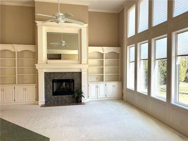 unfurnished living room with crown molding, a fireplace, visible vents, and light carpet