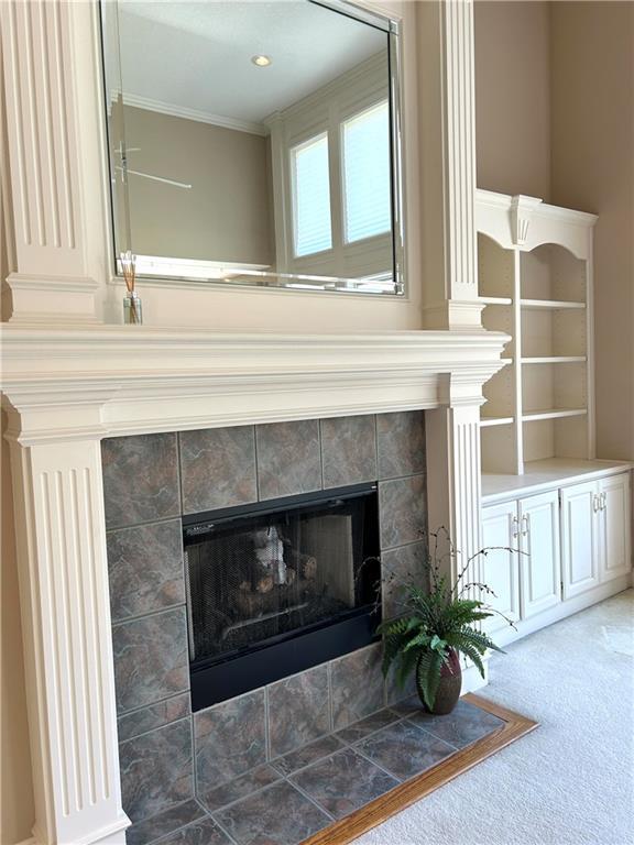 room details featuring a tiled fireplace, crown molding, and carpet floors