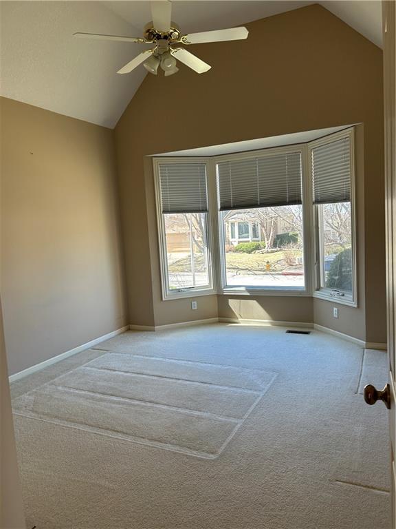 carpeted empty room featuring lofted ceiling, baseboards, a wealth of natural light, and ceiling fan