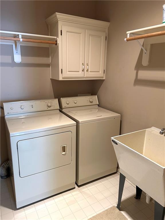 washroom featuring cabinet space, washing machine and dryer, and a sink