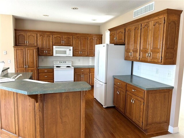 kitchen with white appliances, brown cabinetry, visible vents, dark wood-style flooring, and dark countertops