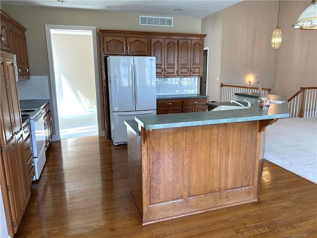 kitchen with visible vents, a large island, dark wood-style floors, white appliances, and decorative backsplash