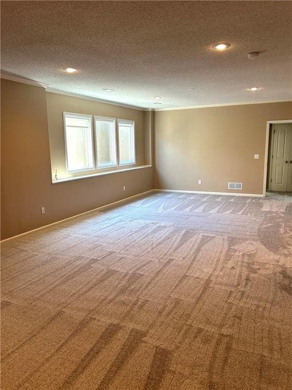 carpeted spare room with visible vents, baseboards, a textured ceiling, and crown molding