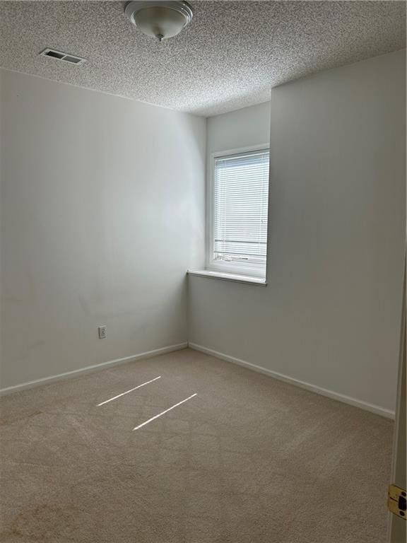 empty room featuring visible vents, baseboards, a textured ceiling, and carpet flooring