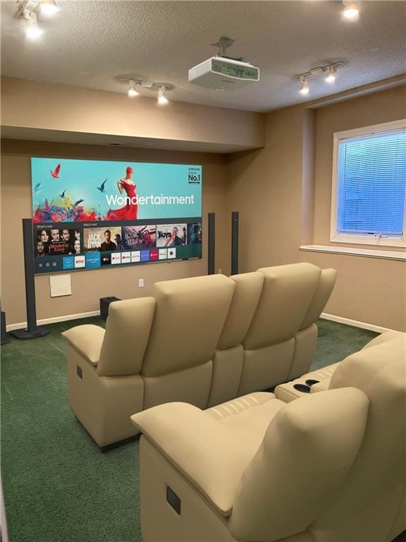 home theater featuring rail lighting, carpet, baseboards, and a textured ceiling