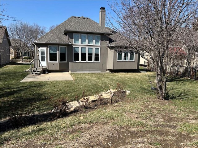 rear view of house with a lawn, a shingled roof, a chimney, and a patio area