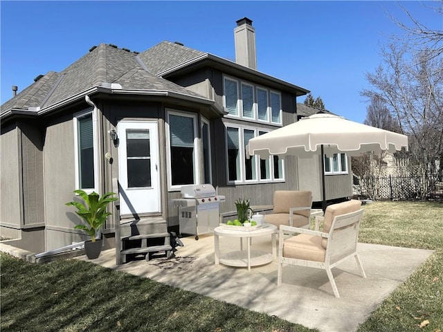 rear view of property featuring a shingled roof, fence, entry steps, a chimney, and a patio