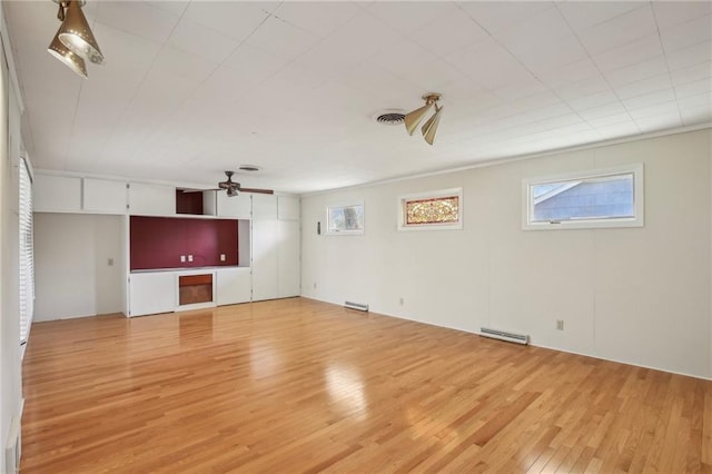 unfurnished living room featuring light wood-style flooring, ceiling fan, plenty of natural light, and a baseboard heating unit