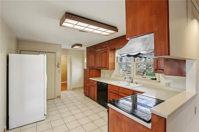 kitchen featuring freestanding refrigerator, black dishwasher, a sink, light countertops, and light tile patterned floors