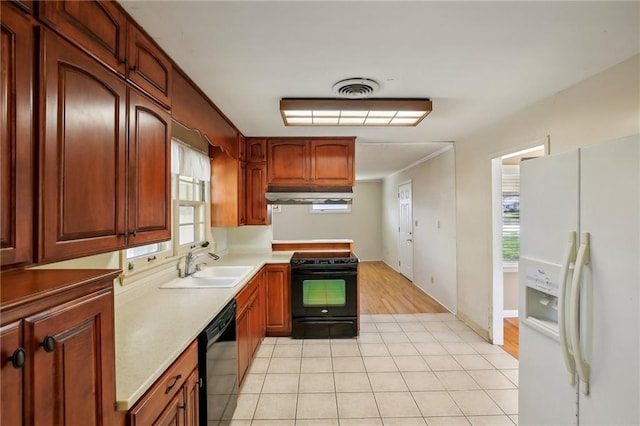 kitchen featuring black appliances, a sink, under cabinet range hood, and healthy amount of natural light