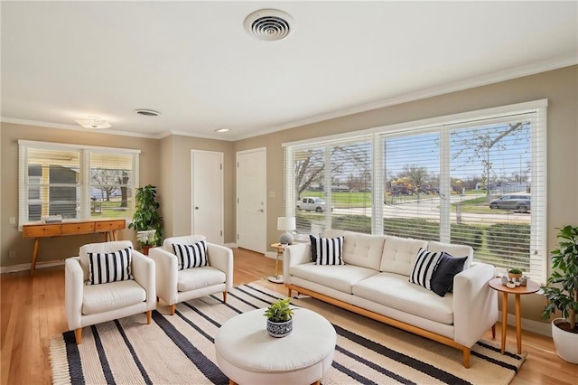 living area with crown molding, baseboards, and light wood-style flooring