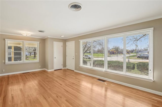 empty room with baseboards, light wood-style flooring, and ornamental molding