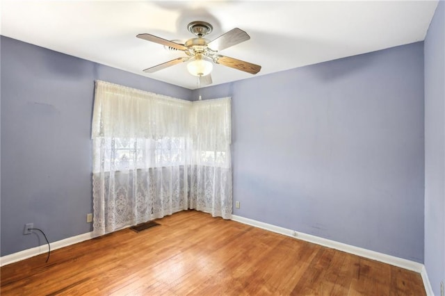 empty room with wood finished floors, ceiling fan, and baseboards