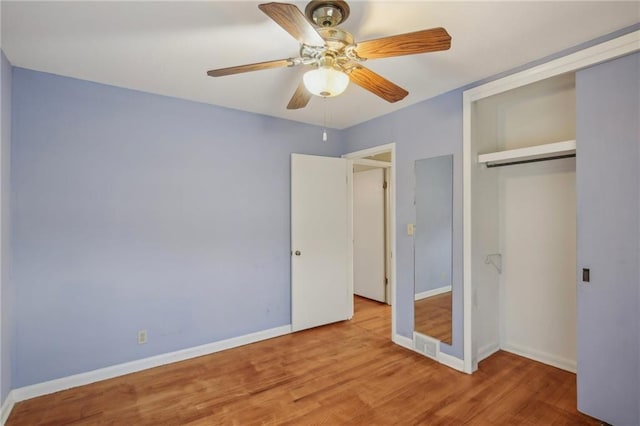 unfurnished bedroom with wood finished floors, a closet, baseboards, and a ceiling fan