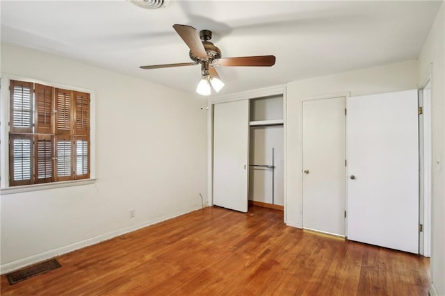 unfurnished bedroom with wood finished floors, a closet, baseboards, and ceiling fan