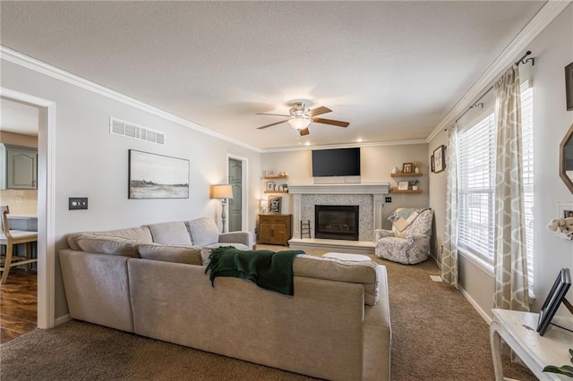 carpeted living area featuring a glass covered fireplace, visible vents, and crown molding