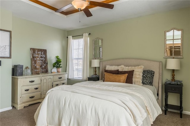 carpeted bedroom with ceiling fan, baseboards, and a raised ceiling