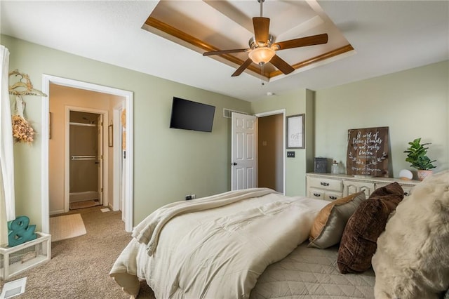 carpeted bedroom featuring visible vents, a tray ceiling, and a ceiling fan