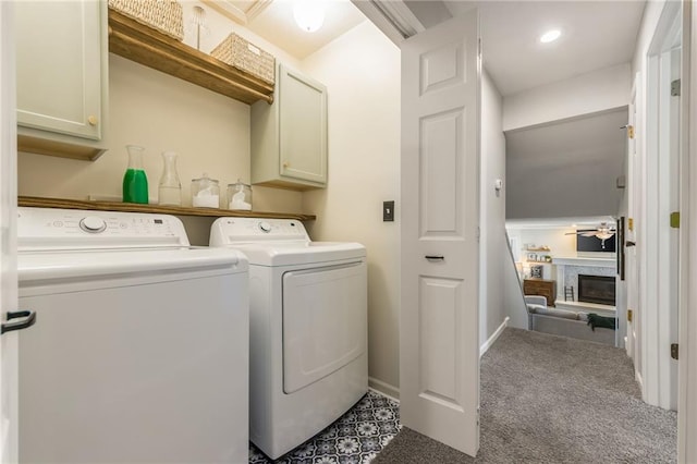 clothes washing area with carpet floors, baseboards, cabinet space, washer and clothes dryer, and a glass covered fireplace