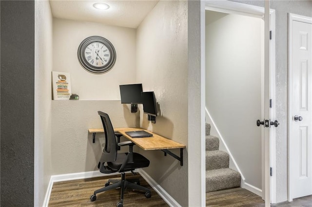 office area with a textured wall, wood finished floors, and baseboards