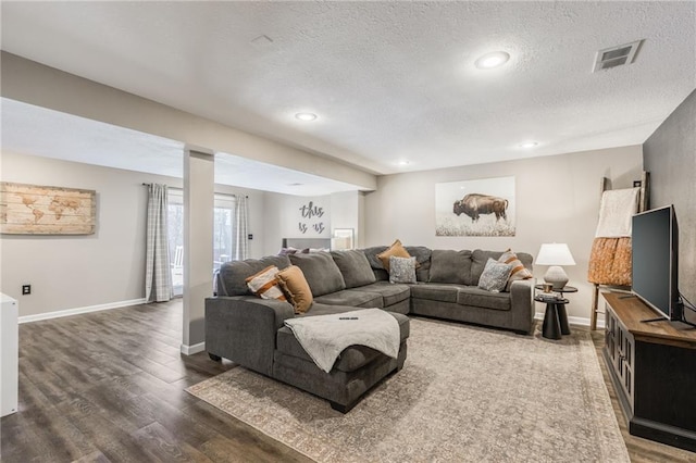 living room with a textured ceiling, recessed lighting, wood finished floors, visible vents, and baseboards