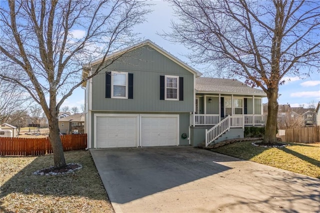 split level home with a porch, concrete driveway, fence, a garage, and stairs