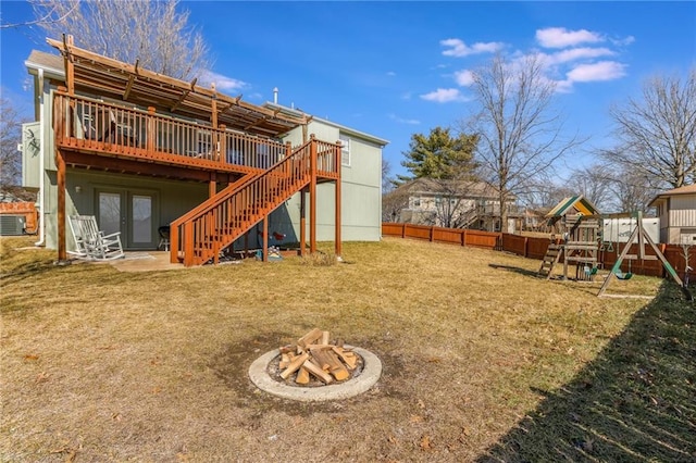 rear view of house featuring french doors, a yard, an outdoor fire pit, fence, and a deck