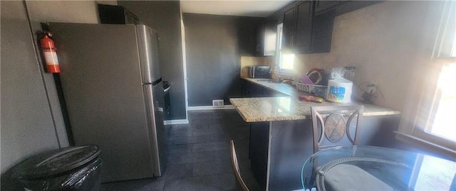 kitchen featuring stainless steel fridge, light stone countertops, sink, and a wealth of natural light