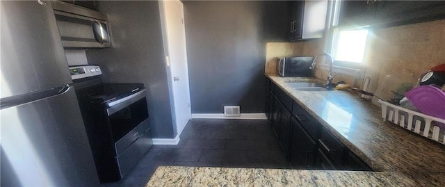 kitchen with tasteful backsplash, sink, light stone counters, and stainless steel appliances