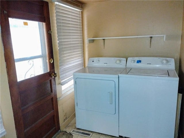 clothes washing area featuring washer and clothes dryer and a wealth of natural light