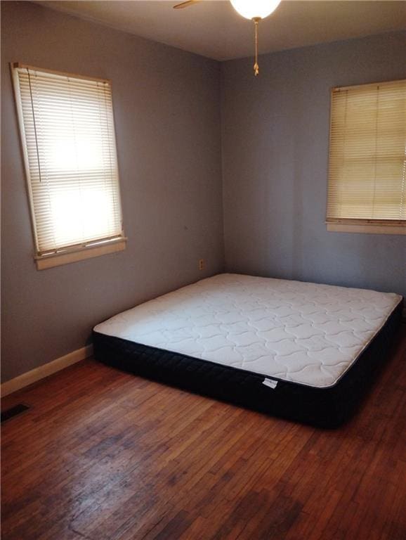 unfurnished bedroom with ceiling fan and wood-type flooring