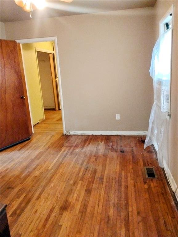 empty room with hardwood / wood-style floors and ceiling fan