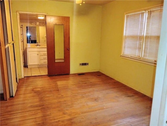 unfurnished room featuring plenty of natural light, sink, and light hardwood / wood-style flooring